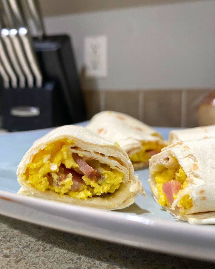 Breakfast burrito made with egg, ham, and cheese on a plate