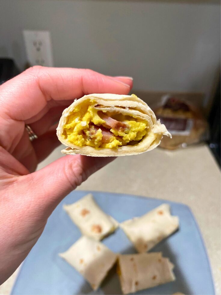 Hand holding freezer-friendly burrito made with egg, ham, and cheese