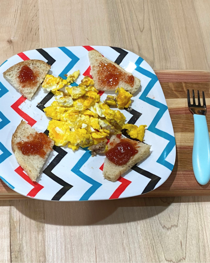 Kid-approved scrambled eggs & sausage on a plate with sourdough toast and jam