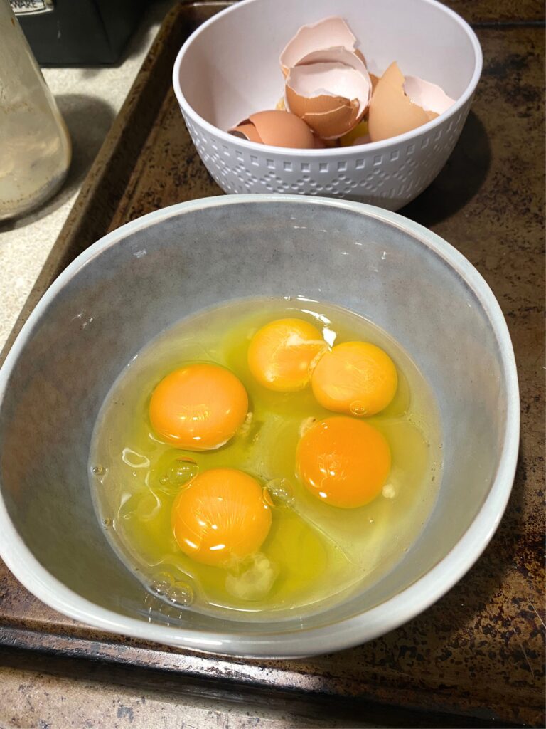 Five cracked eggs in a gray bowl