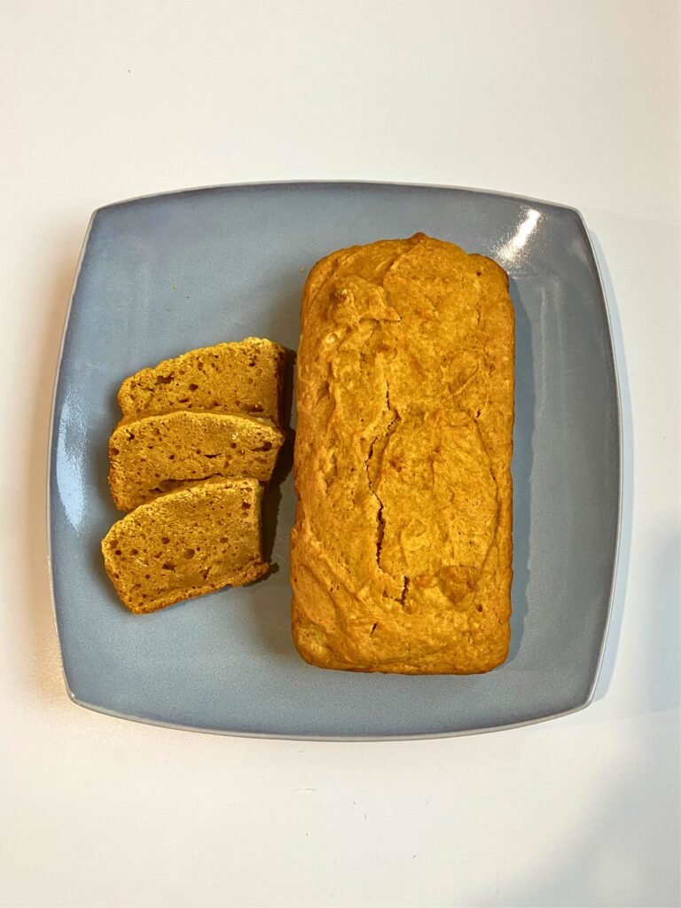 Above shot of three slices of pumpkin bread on the left and one full loaf on the right