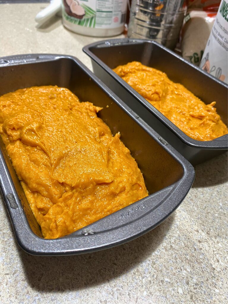 Close up of orange pumpkin bread batter in two loaf pans