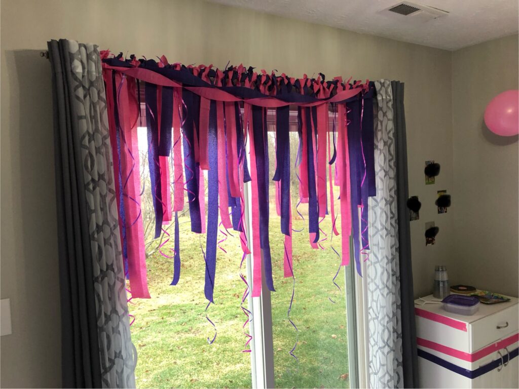 Patio door decorated with pink and purple paper streamers and curly ribbon