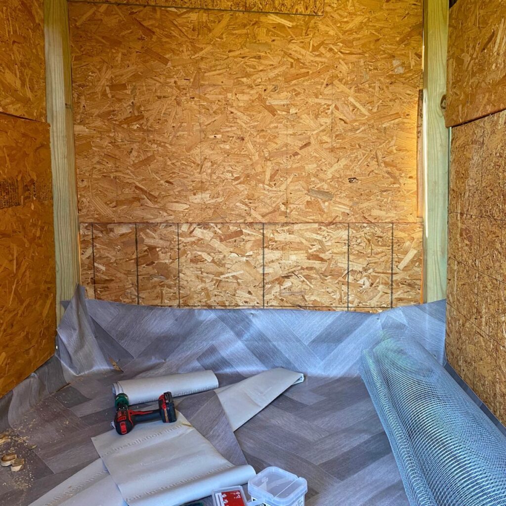 unfinished interior of a chicken coop showing vinyl flooring before bedding on top