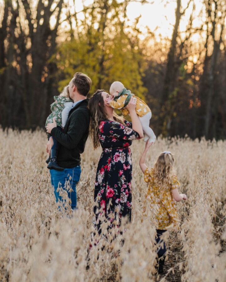 Man and woman holding three young children in a bean field