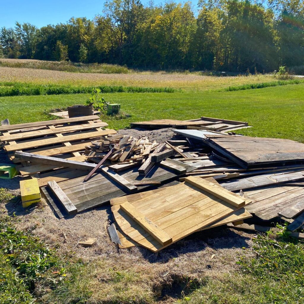 A large pile of scrap wood fencing in a heap to be sorted for use as a new chicken coop