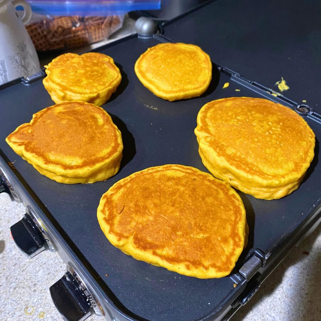 Homemade pumpkin pancakes cooking on a griddle