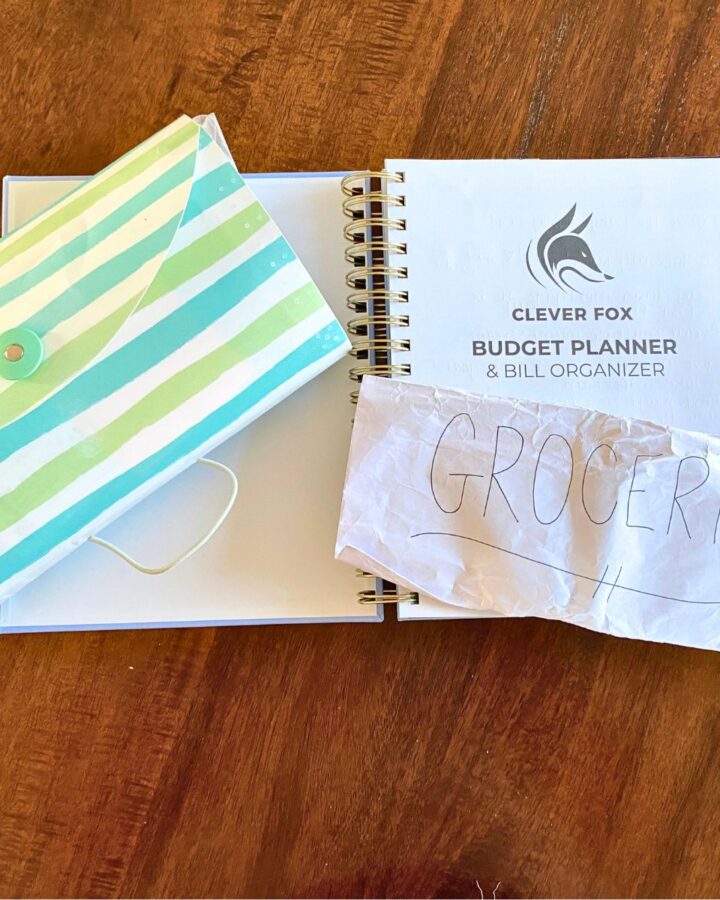 budget planner & bill organizer, accordion filing system for cash envelope system, and envelope labeled "Groceries" on a tabletop