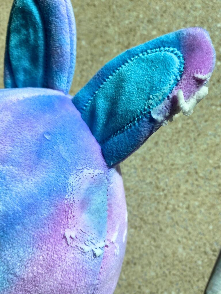 A purple and blue bunny that was stained by a baby with the stomach flu. On the yellow and white stains there is a baking soda and vinegar paste to sit for five minutes before rinsing with warm water.